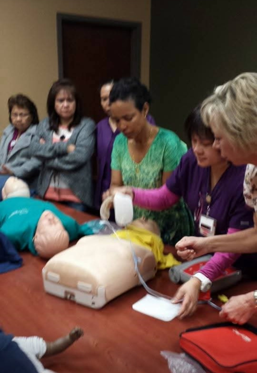 CPR class practicing with AED trainer and adult mannequins